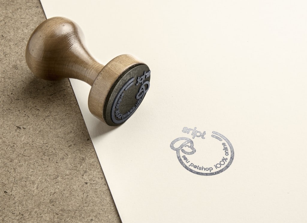 Wooden hand stamp on cream cardstock beside a grey ink impression of the circular Serelepet mark: abbreviated wordmark, minimal line dog profile, and curved tagline "seu petshop 100% online", on textured neutral fibreboard.
